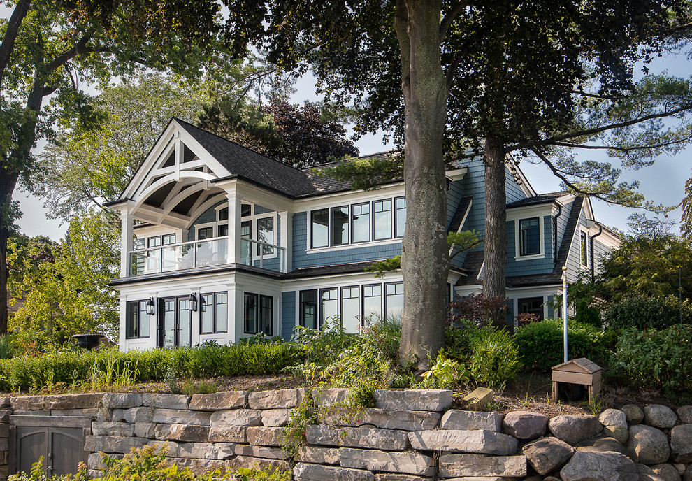 Imagen de fachada de casa azul de estilo americano grande de tres plantas con revestimientos combinados, tejado a dos aguas y tejado de teja de madera