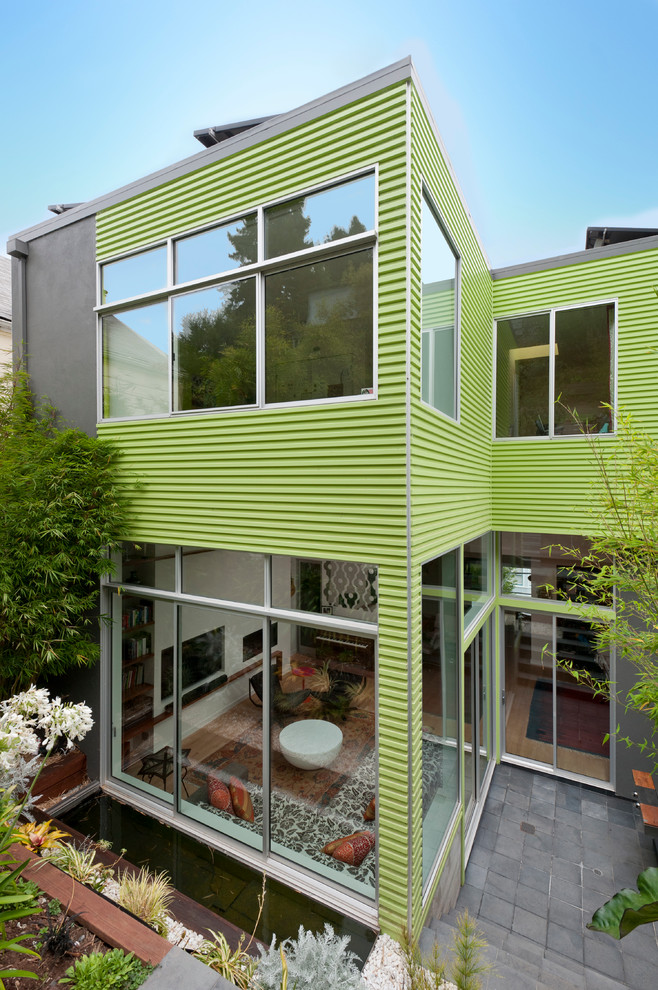 Cette photo montre une façade de maison verte tendance à un étage avec un toit plat.