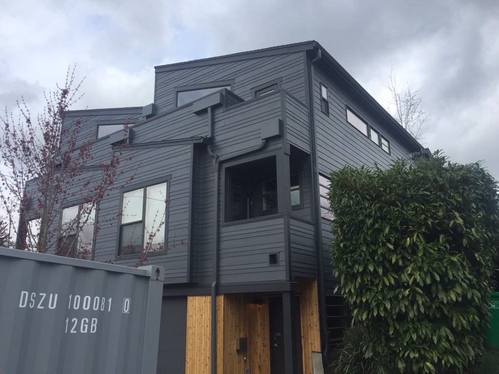 Inspiration pour une façade de maison de ville grise minimaliste en panneau de béton fibré de taille moyenne et à un étage avec un toit en appentis et un toit en shingle.