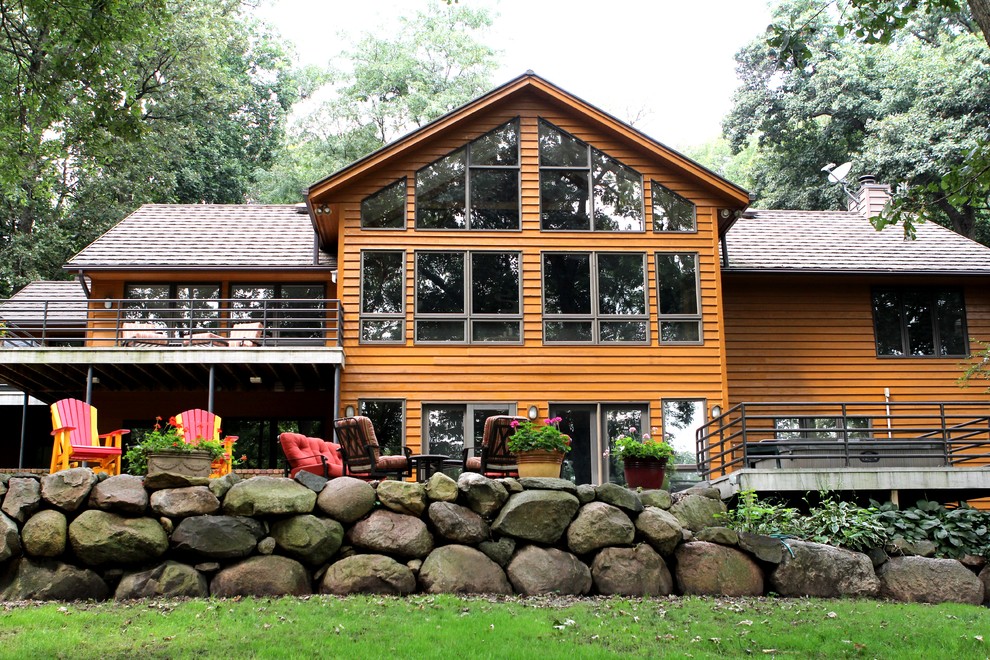 Aménagement d'une grande façade de maison marron campagne en bois à un étage avec un toit à deux pans.
