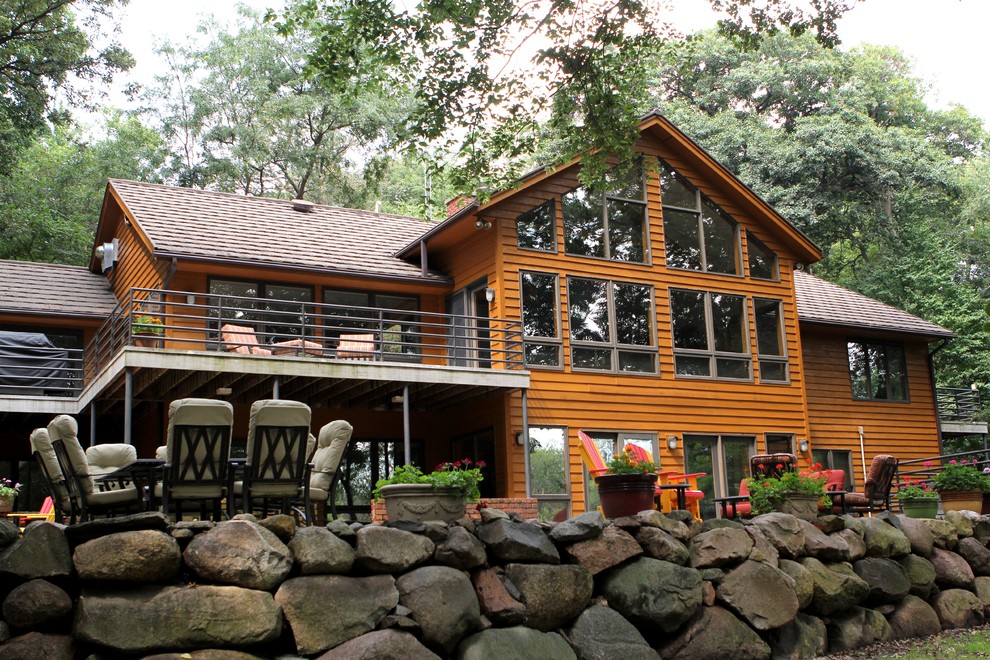 Réalisation d'une grande façade de maison marron champêtre en bois à un étage avec un toit à deux pans.