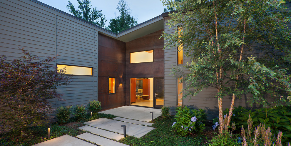 Aménagement d'une grande façade de maison grise contemporaine de plain-pied avec un revêtement mixte, un toit en appentis et un toit en métal.