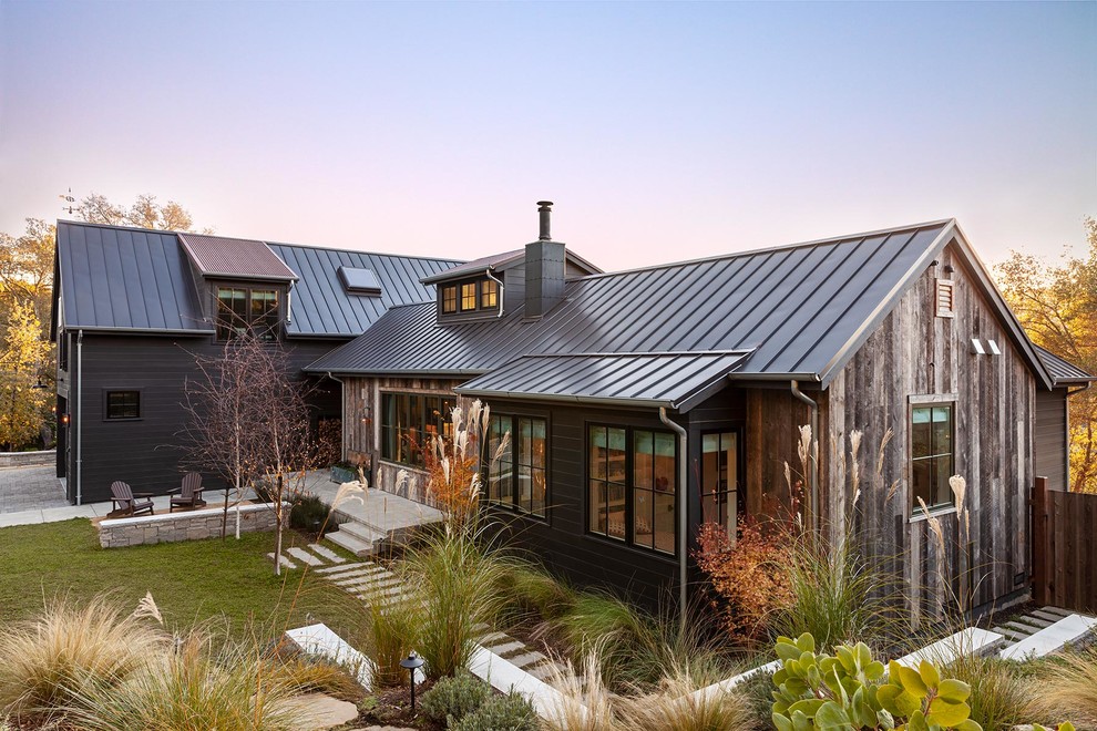 Imagen de fachada de casa marrón de estilo de casa de campo de una planta con revestimientos combinados, tejado a dos aguas y tejado de metal