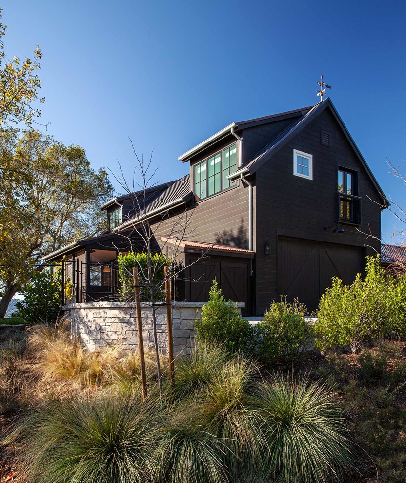 Стильный дизайн: двухэтажный, коричневый частный загородный дом в стиле кантри с двускатной крышей и крышей из гибкой черепицы - последний тренд