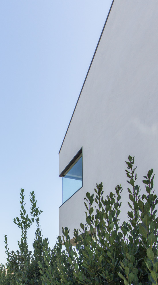 Idée de décoration pour une grande façade de maison blanche minimaliste en stuc à un étage avec un toit plat et un toit en métal.