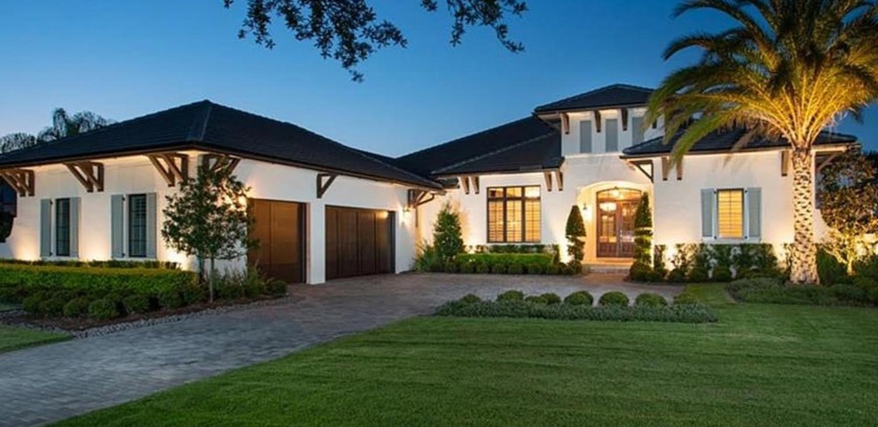 Large craftsman white one-story stucco house exterior idea in Orlando with a hip roof and a shingle roof