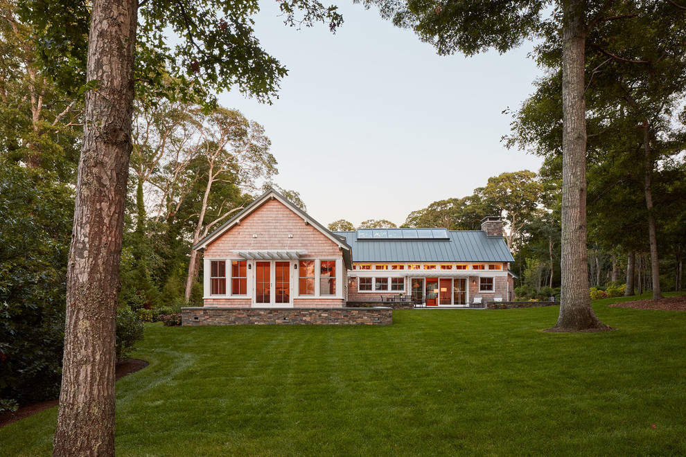 Foto della villa beige country a un piano con rivestimento in legno, tetto a capanna e copertura in metallo o lamiera