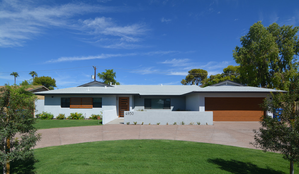 Cette image montre une grande façade de maison bleue vintage en stuc de plain-pied avec un toit à quatre pans.