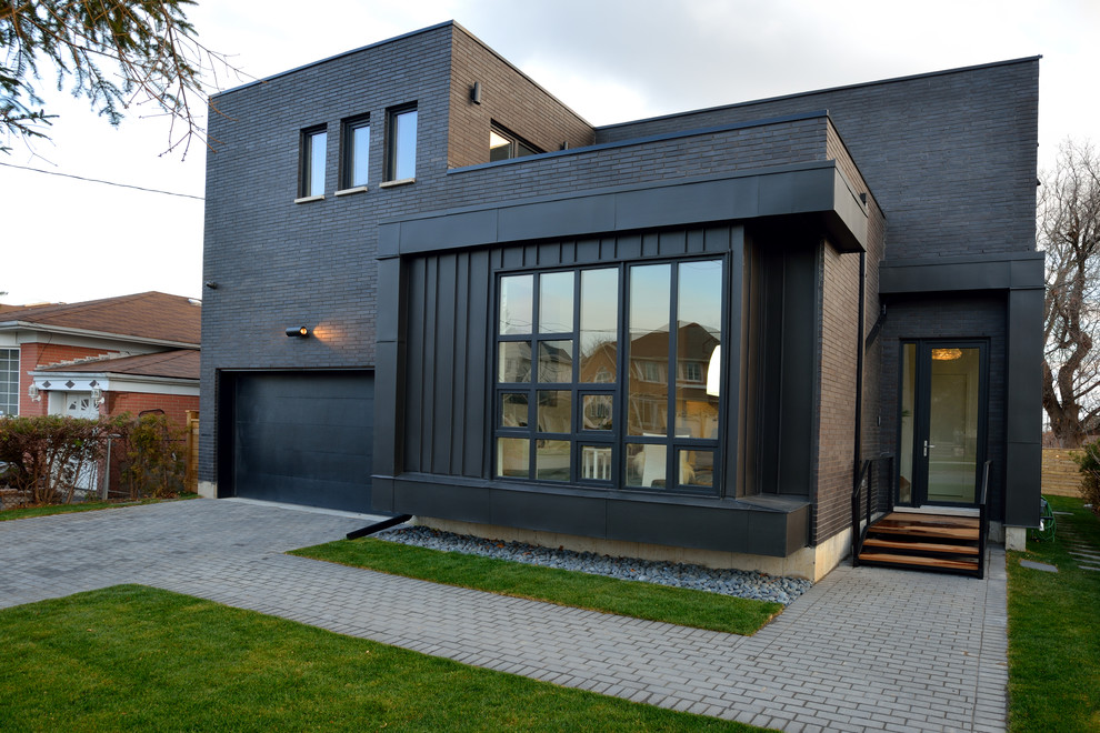 Cette image montre une grande façade de maison noire design à un étage avec un revêtement mixte et un toit plat.