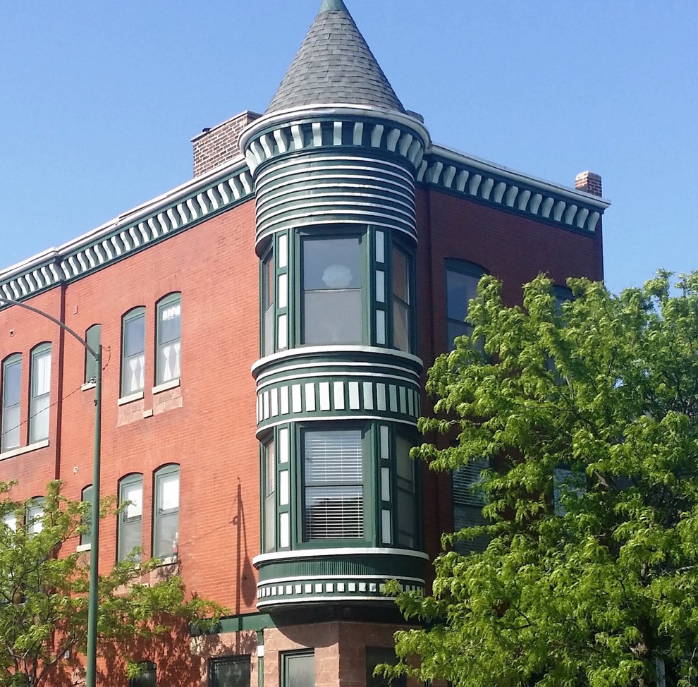 Immagine della facciata di una casa grande verde vittoriana a tre piani con rivestimento in mattoni e tetto piano