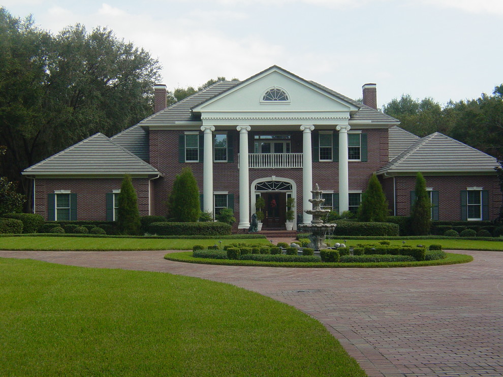 Inspiration for a large timeless red two-story brick house exterior remodel in Tampa with a hip roof