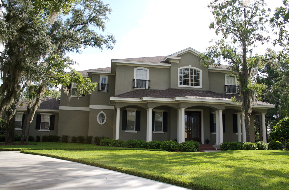 Large traditional gray two-story stucco house exterior idea in Tampa with a hip roof and a shingle roof