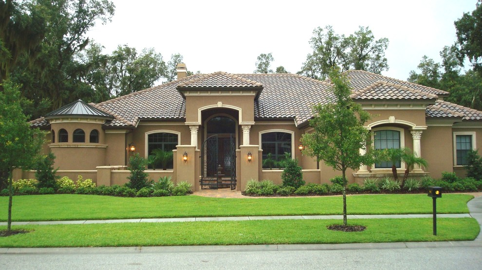 Exempel på ett stort medelhavsstil brunt hus, med allt i ett plan, stuckatur, valmat tak och tak med takplattor