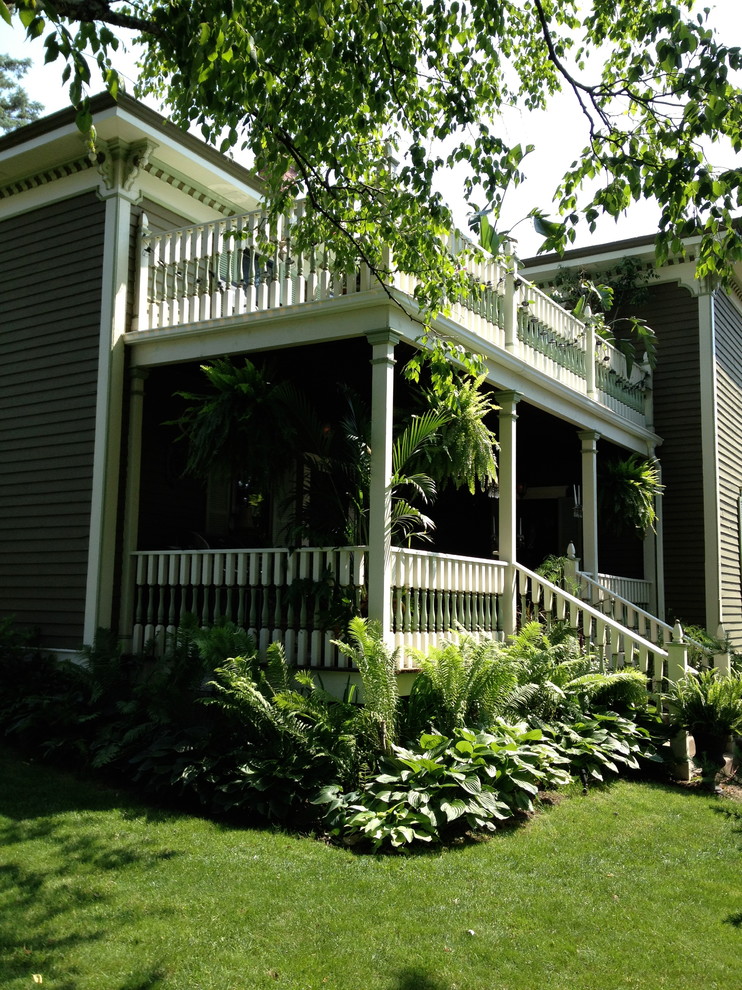 Esempio della facciata di una casa verde classica a due piani con rivestimento in legno