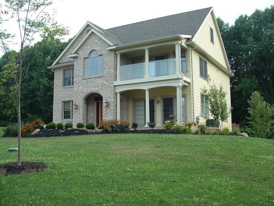 Modelo de fachada de casa multicolor de estilo americano de tamaño medio de dos plantas con revestimientos combinados, tejado a dos aguas y tejado de teja de madera