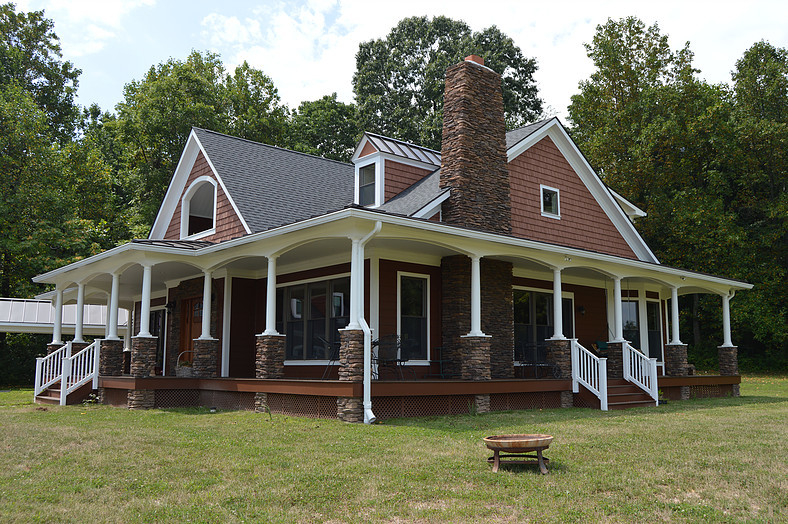 Aménagement d'une grande façade de maison marron campagne en bois à un étage avec un toit à quatre pans et un toit en shingle.