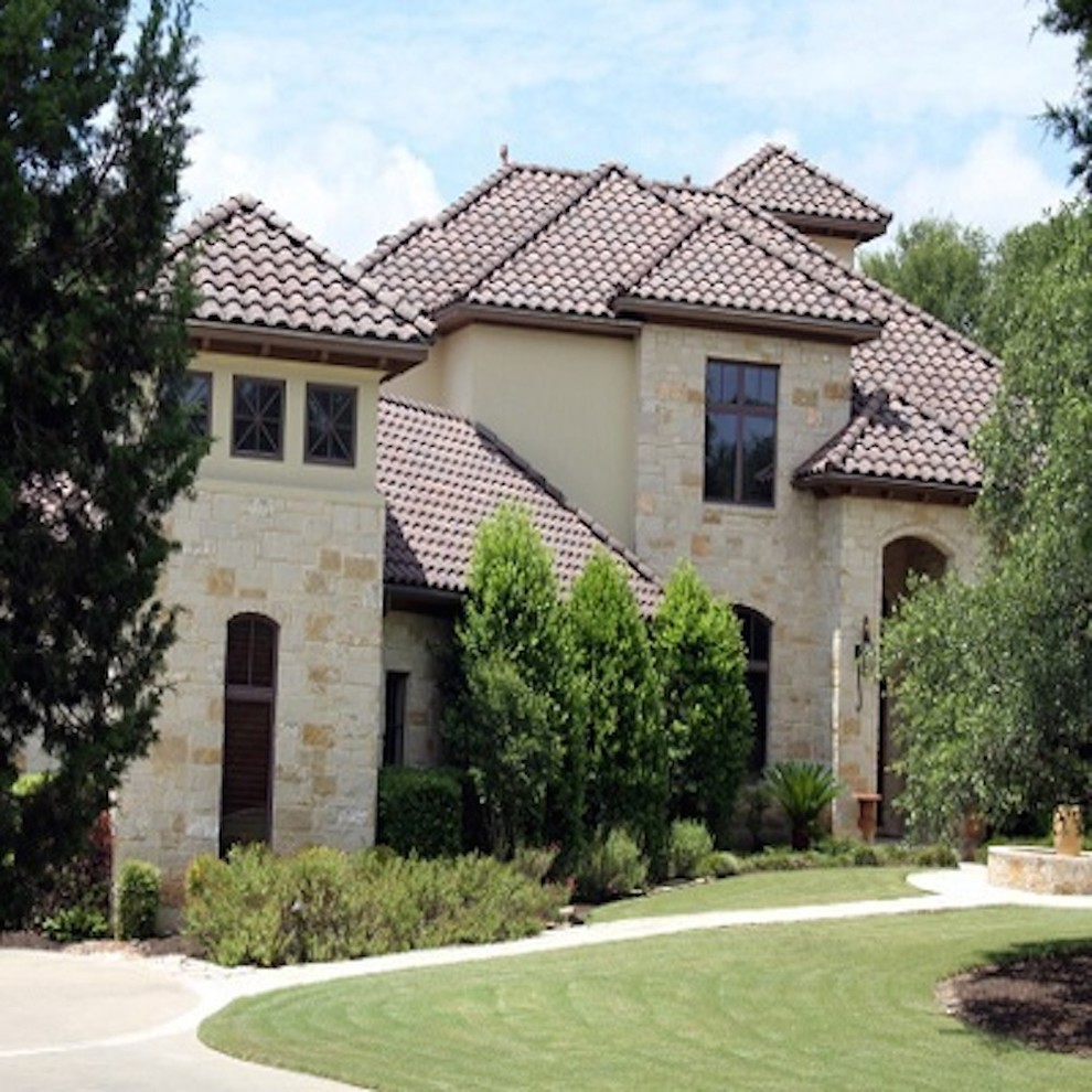 Example of a large tuscan beige three-story stone exterior home design in Austin