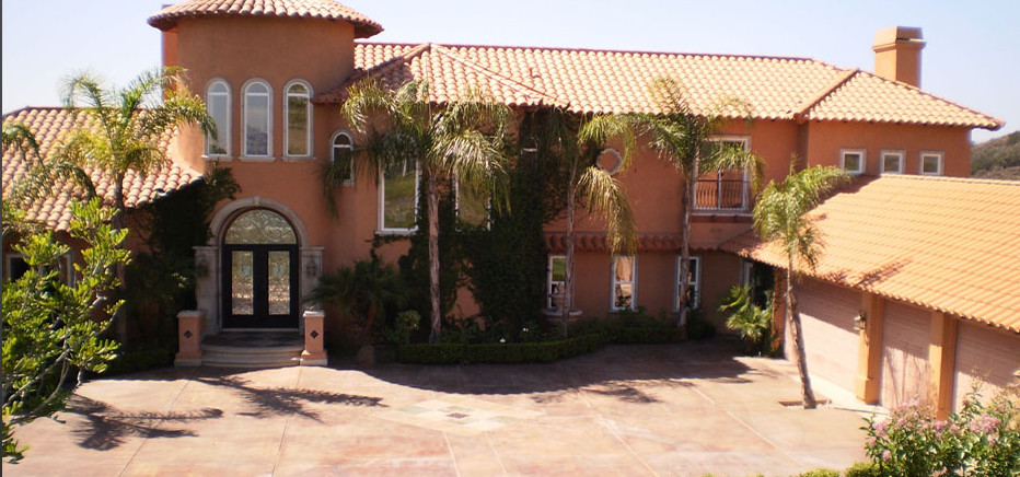 На фото: большой, двухэтажный, коричневый частный загородный дом в средиземноморском стиле с облицовкой из цементной штукатурки, вальмовой крышей и черепичной крышей с