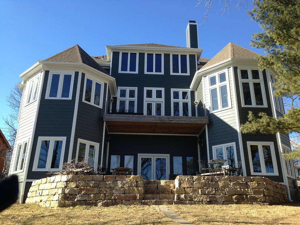 Esempio della facciata di una casa grande blu american style a tre piani con rivestimento in legno e tetto a capanna