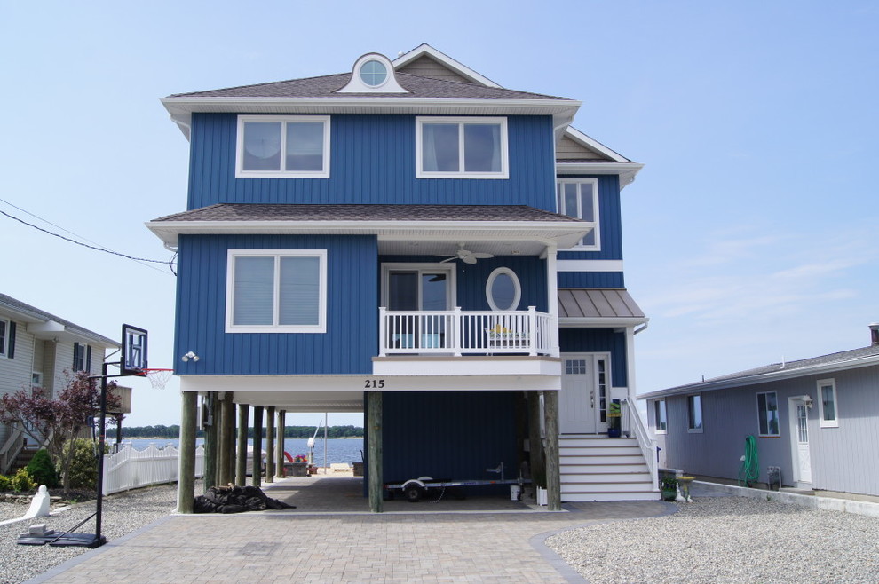 Diseño de fachada de casa azul costera de tamaño medio de dos plantas con revestimiento de madera, tejado a cuatro aguas y tejado de varios materiales