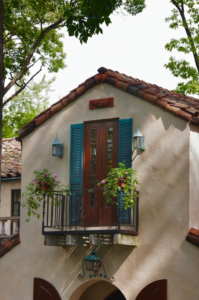 Réalisation d'une petite façade de maison beige méditerranéenne en stuc à un étage avec un toit à deux pans.