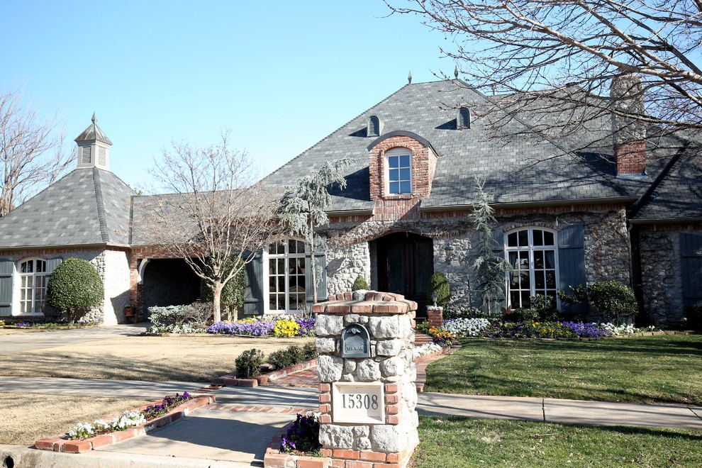 This is an example of a large and gey classic bungalow house exterior in Oklahoma City with mixed cladding and a half-hip roof.