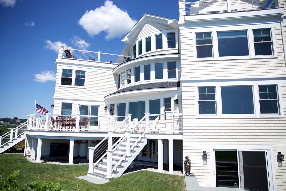 Example of a large beach style white three-story wood gable roof design in Providence