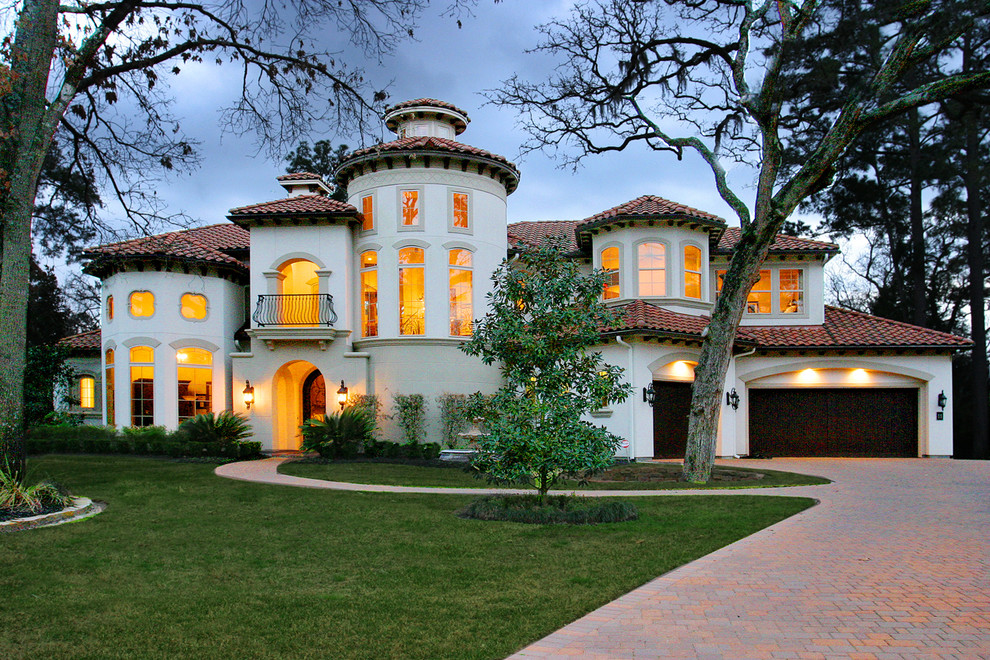Inspiration for a large mediterranean white two-story stucco house exterior remodel in Houston with a hip roof and a tile roof