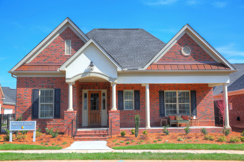 Cette photo montre une façade de maison rouge chic en brique de taille moyenne et à un étage avec un toit à deux pans.