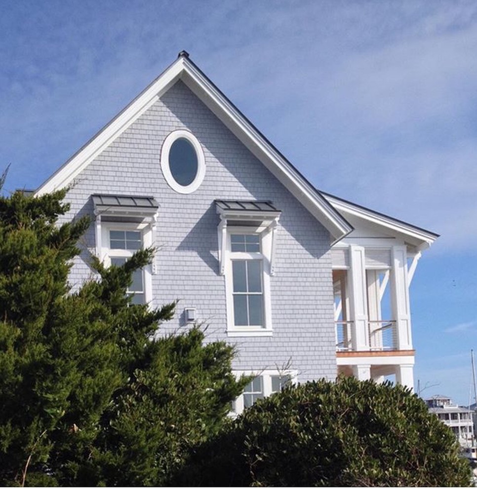 Modelo de fachada de casa gris marinera grande de tres plantas con revestimiento de madera, tejado a dos aguas y tejado de metal