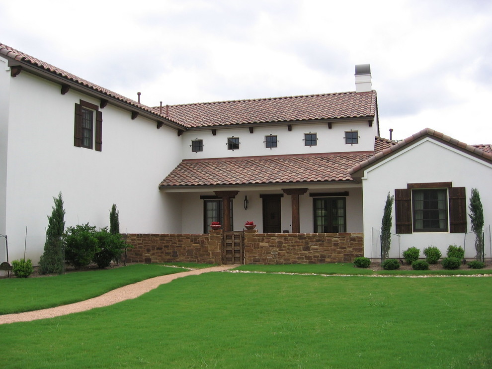 This is an example of a large and white mediterranean two floor render house exterior in Austin with a pitched roof.