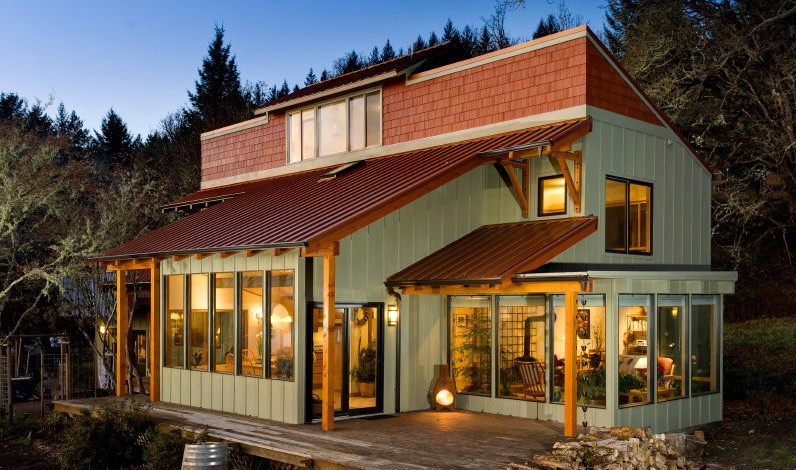 На фото: трехэтажный, деревянный, зеленый частный загородный дом среднего размера в стиле кантри с односкатной крышей и металлической крышей с