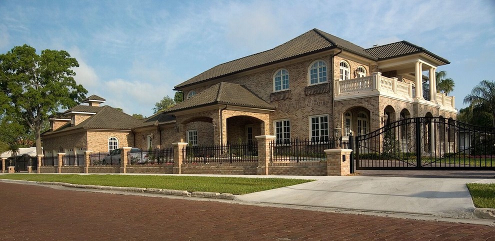 На фото: большой, двухэтажный, кирпичный, коричневый частный загородный дом в классическом стиле с вальмовой крышей и черепичной крышей с