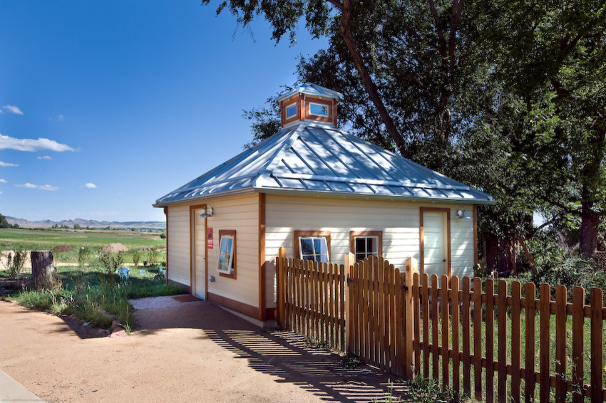 Immagine della villa country a un piano di medie dimensioni con rivestimento in legno, tetto a padiglione e copertura in metallo o lamiera