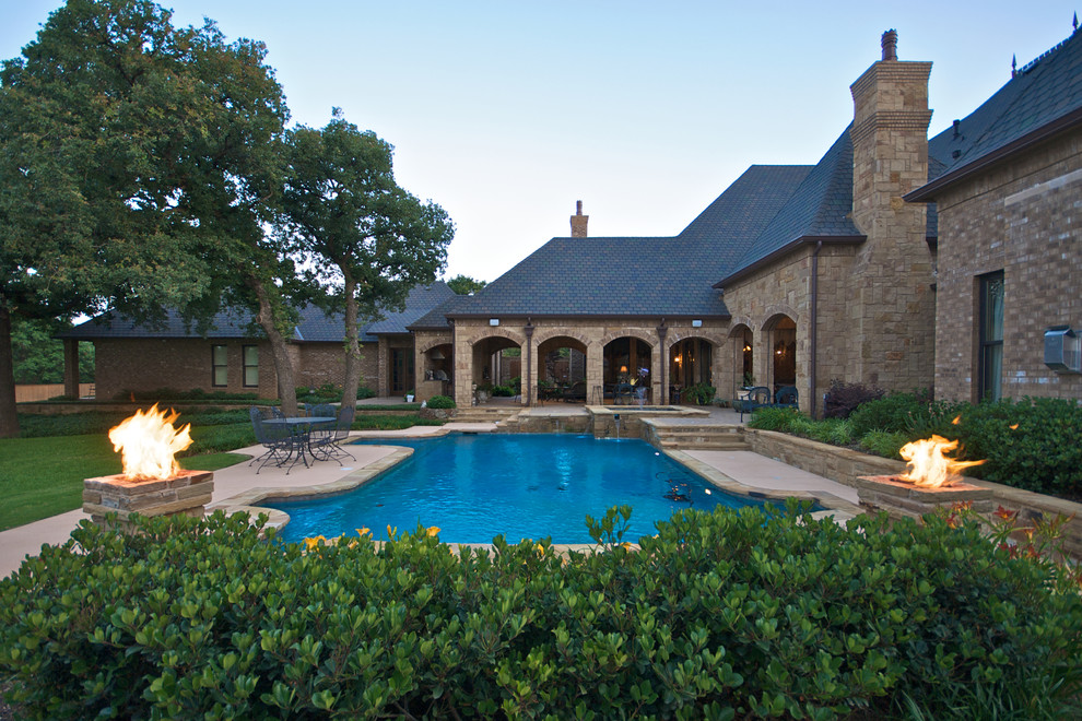 Large tuscan two-story stone exterior home photo in Dallas with a hip roof