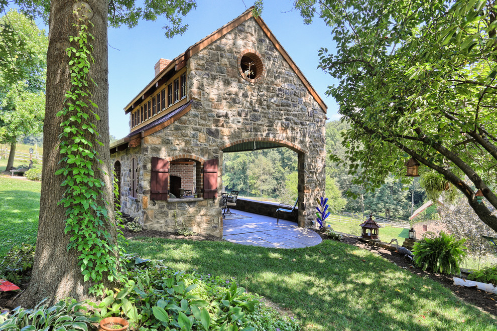 Foto della facciata di una casa country a un piano con rivestimento in pietra e tetto a capanna