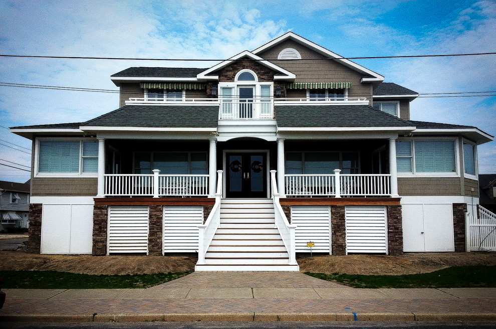 Cette photo montre une grande façade de maison grise bord de mer à deux étages et plus avec un toit à quatre pans.
