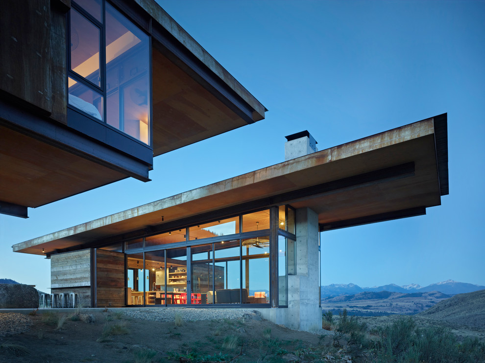 Réalisation d'une façade de maison grise design en béton de plain-pied avec un toit en appentis.