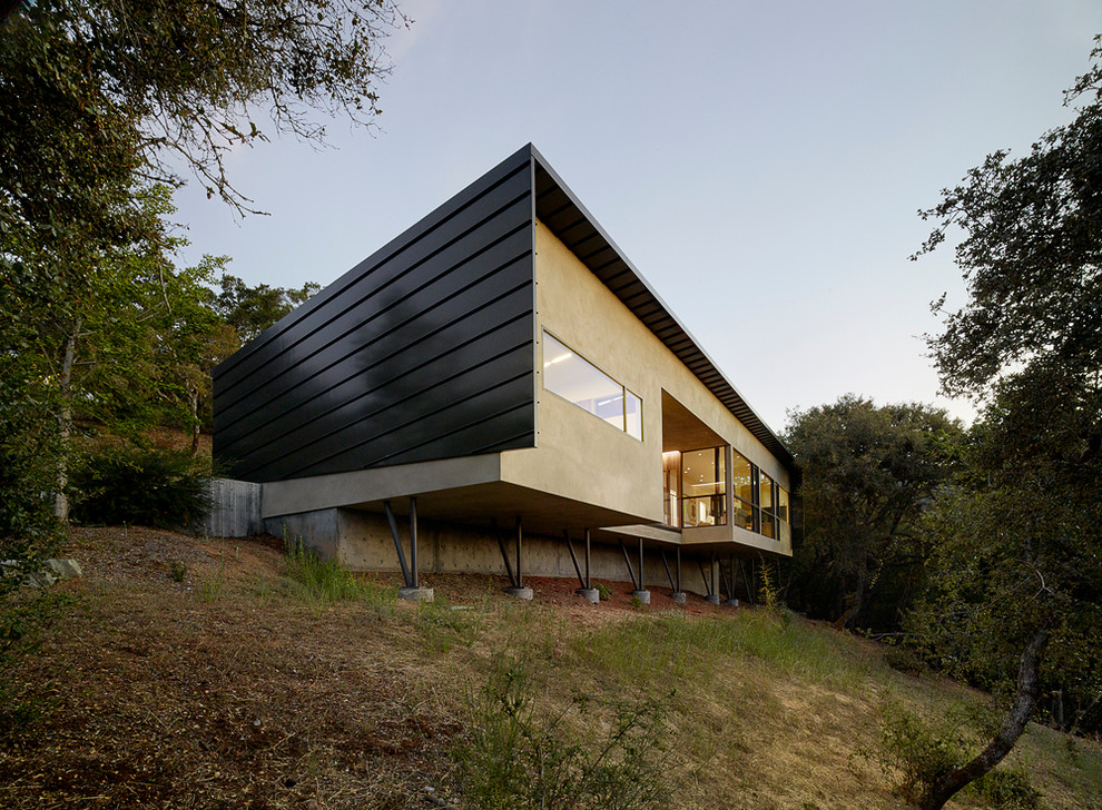 Стильный дизайн: маленький, одноэтажный, серый дом в стиле модернизм с облицовкой из цементной штукатурки и односкатной крышей для на участке и в саду - последний тренд