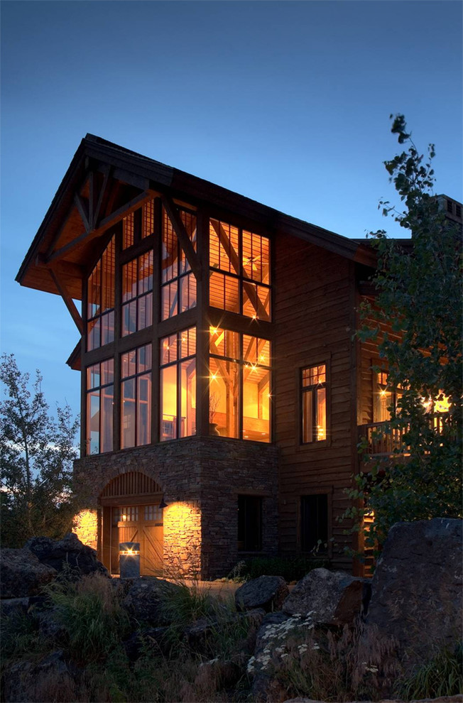 Стильный дизайн: большой, трехэтажный, деревянный, коричневый дом в стиле рустика с двускатной крышей - последний тренд
