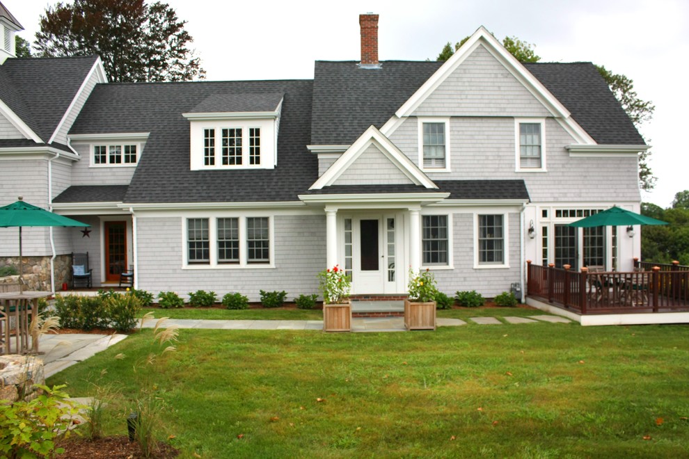 На фото: двухэтажный, деревянный, серый дом среднего размера в классическом стиле с двускатной крышей