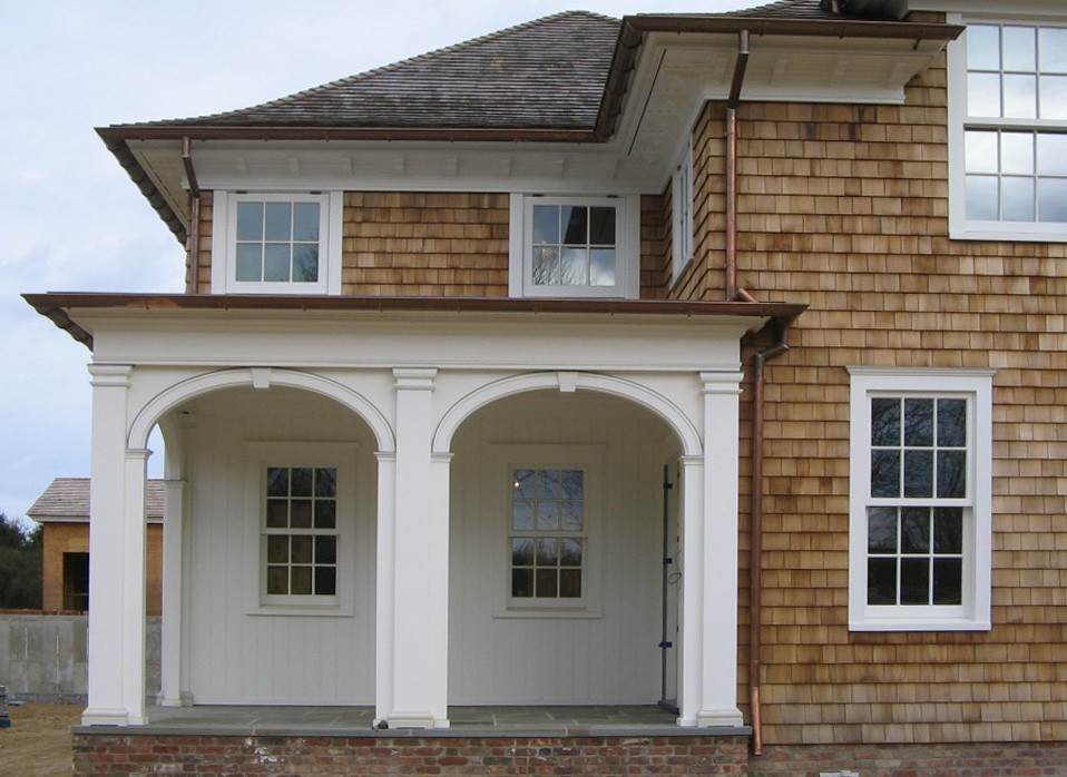 Idée de décoration pour une grande façade de maison marron marine en bois à un étage avec un toit à quatre pans et un toit en shingle.