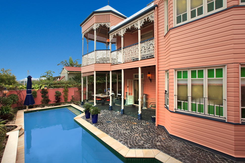 Ornate pink two-story house exterior photo in Brisbane with a hip roof and a metal roof