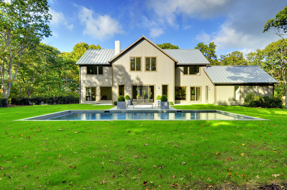 Imagen de fachada de casa beige de estilo de casa de campo grande de dos plantas con revestimiento de madera, tejado a dos aguas y tejado de metal