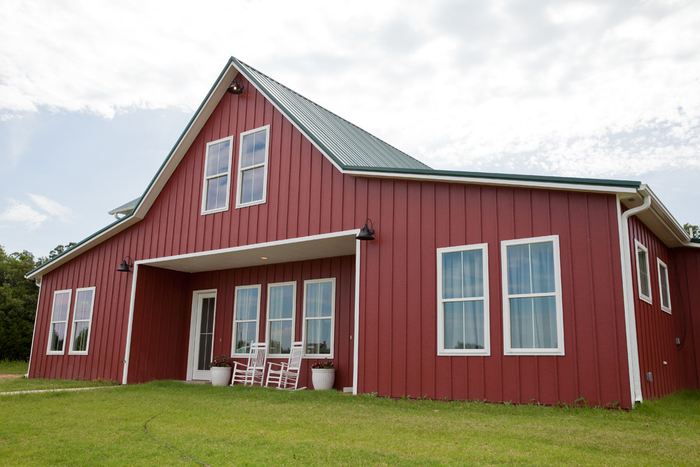 Réalisation d'une grande façade de maison rouge champêtre en bois à un étage avec un toit à deux pans et un toit en métal.