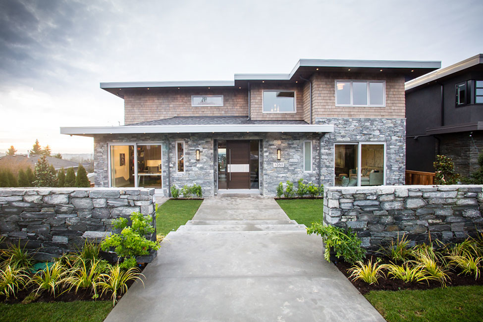 This is an example of a gey contemporary house exterior in Vancouver with three floors and stone cladding.