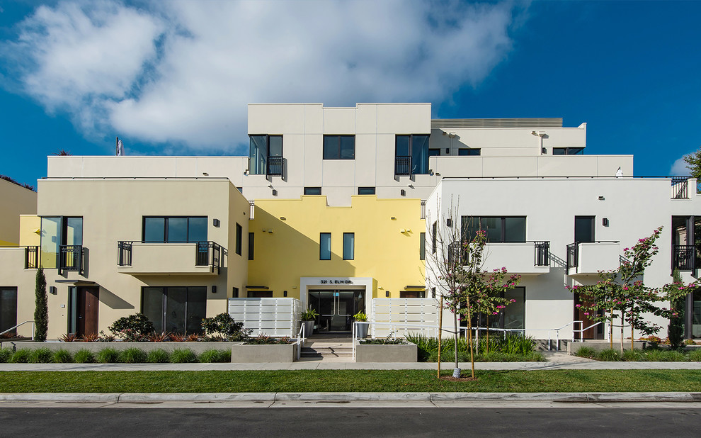 Свежая идея для дизайна: большой, трехэтажный, желтый многоквартирный дом в стиле модернизм с облицовкой из цементной штукатурки и плоской крышей - отличное фото интерьера