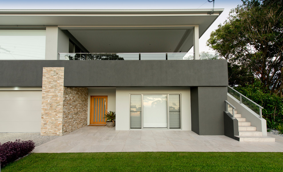 На фото: большой, двухэтажный, бежевый частный загородный дом в стиле модернизм с металлической крышей, облицовкой из бетона и вальмовой крышей