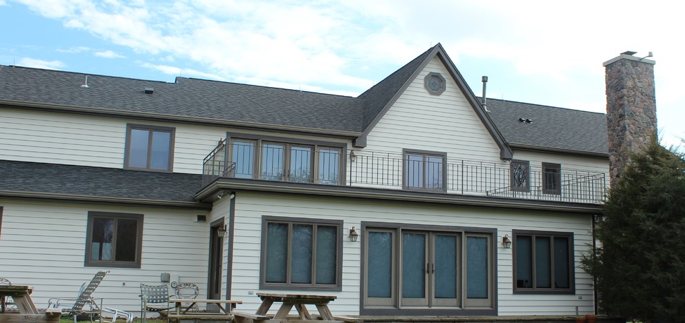 Imagen de fachada blanca de estilo americano grande de dos plantas con revestimiento de madera y tejado a dos aguas