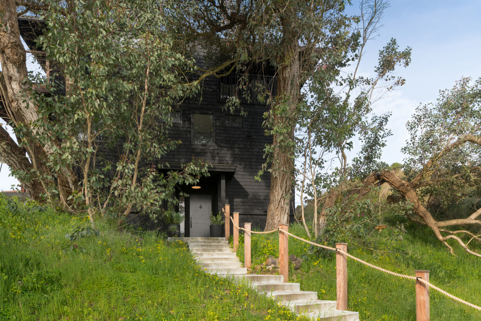 Cette photo montre une façade de maison noire bord de mer en bois de taille moyenne et à deux étages et plus.